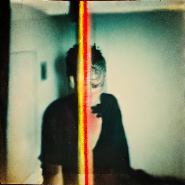 polaroid of strange man with yellow and red vertical stripe crossing him out